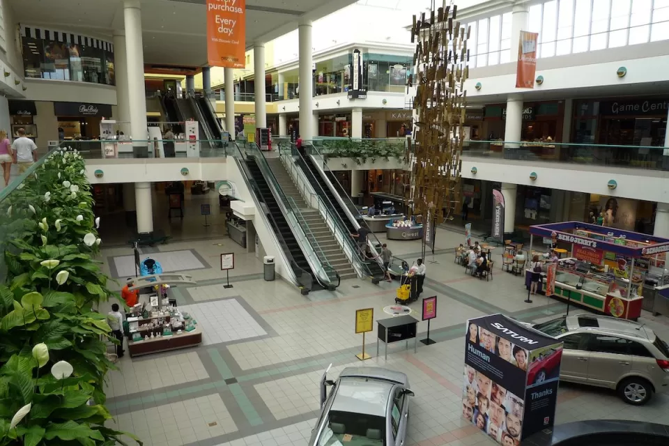 View form second story inside Southdale Mall in Edina, Minnesota with escalators and model cars parked on downstairs floor.